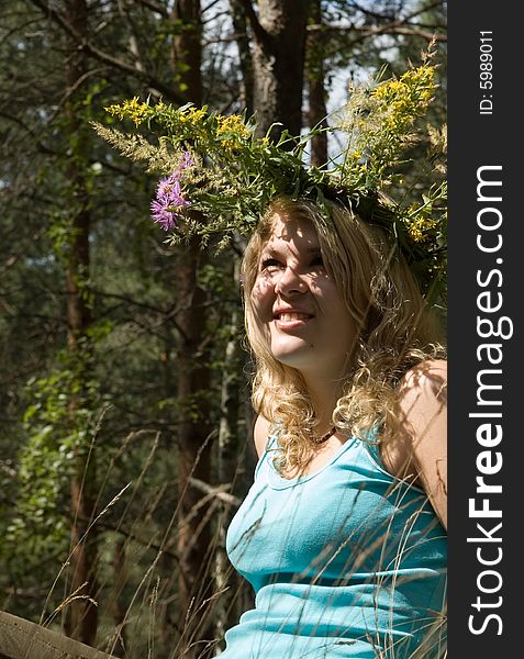 Young beautiful blonde in a forest with flowers diadem. Young beautiful blonde in a forest with flowers diadem