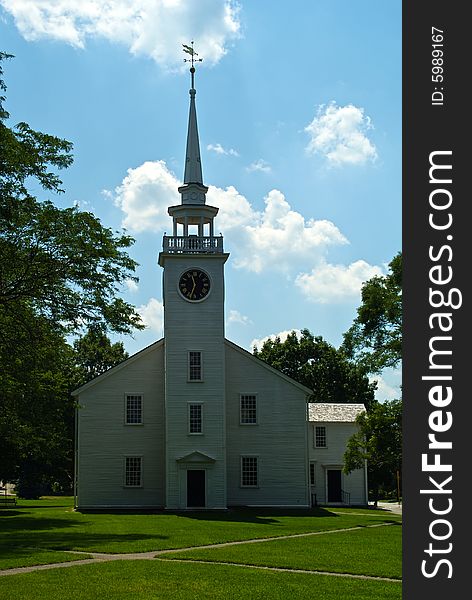 Classic new england white church with clock tower and weather vane
