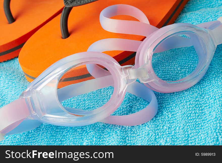 Pink swimming glasses on a blue towel