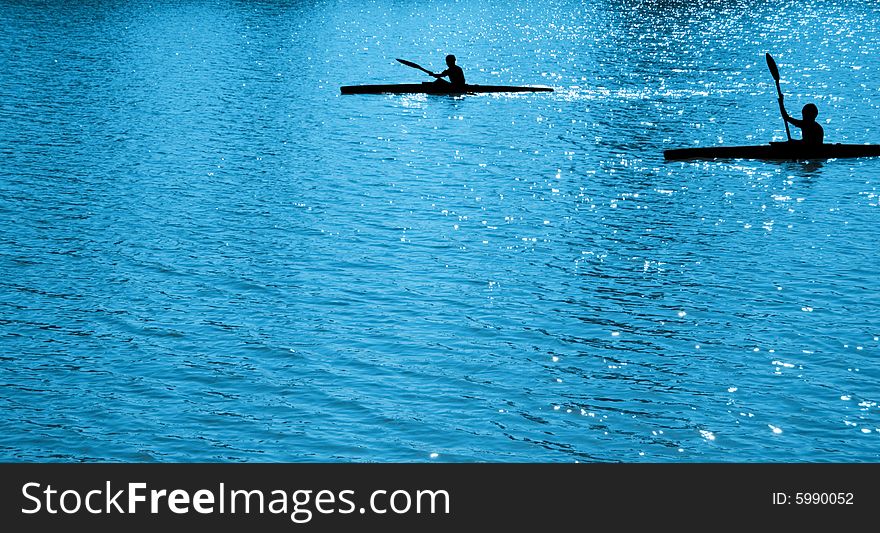 A black silhouettes of  child sportsmen on paddles (kayaks). A black silhouettes of  child sportsmen on paddles (kayaks)