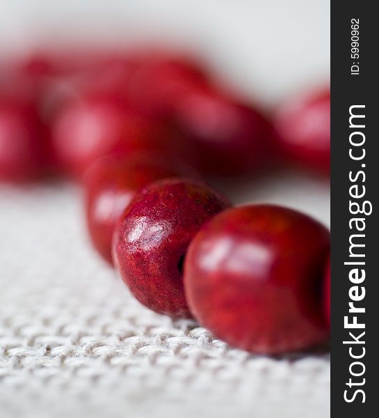 Red wooden beads are on a background from fabric