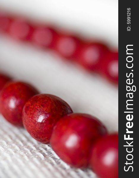 Red wooden beads are on a background from fabric - macro