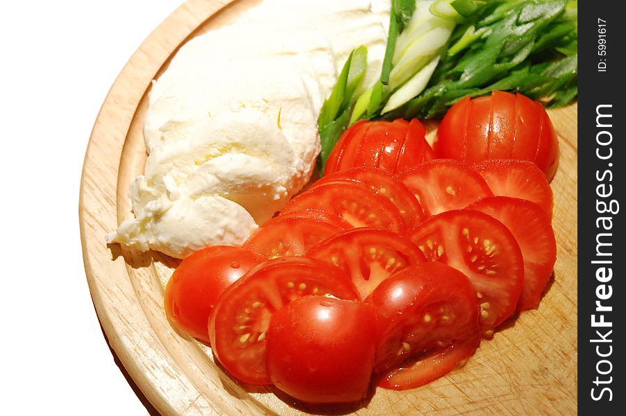 Slices of fresh mozzarella, tomatoes and spring onion on wood plate. Slices of fresh mozzarella, tomatoes and spring onion on wood plate.