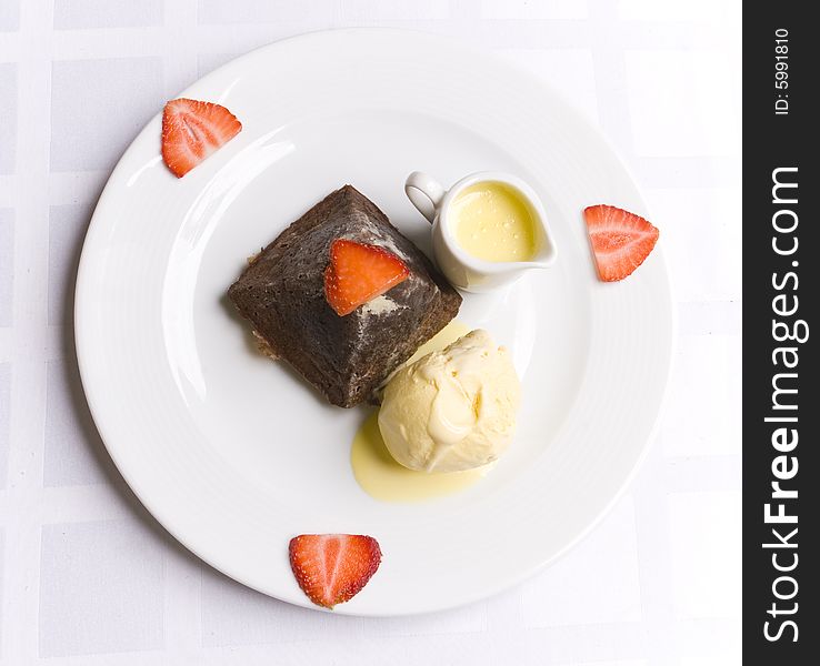 Chocolate dessert with strawberry, ice cream and milky sauce on white plate