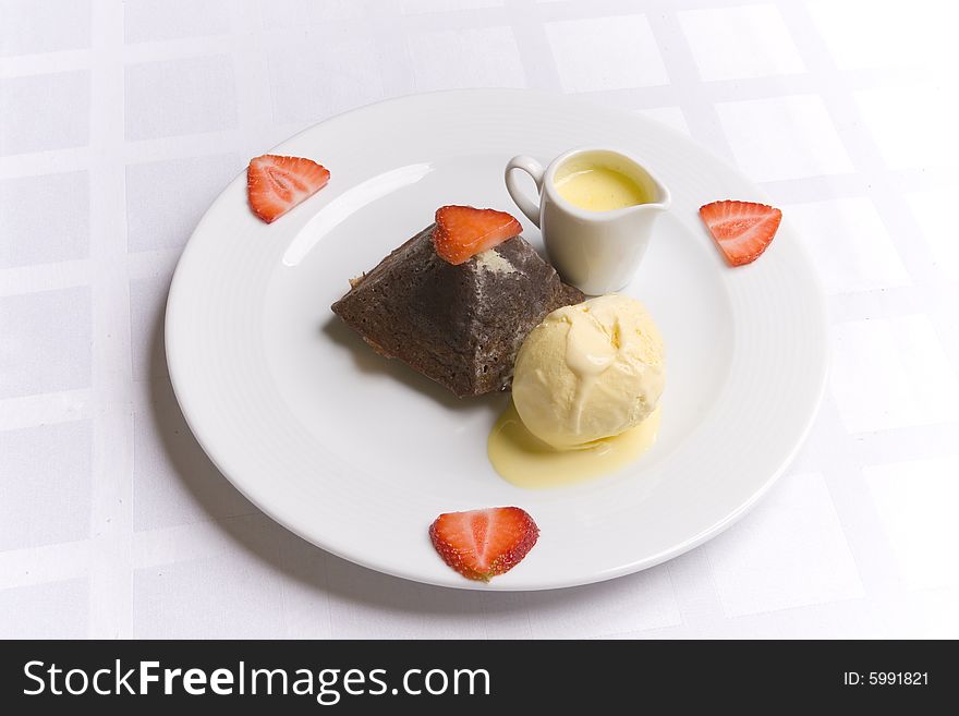 Chocolate dessert with strawberry, ice cream and milky sauce on white plate