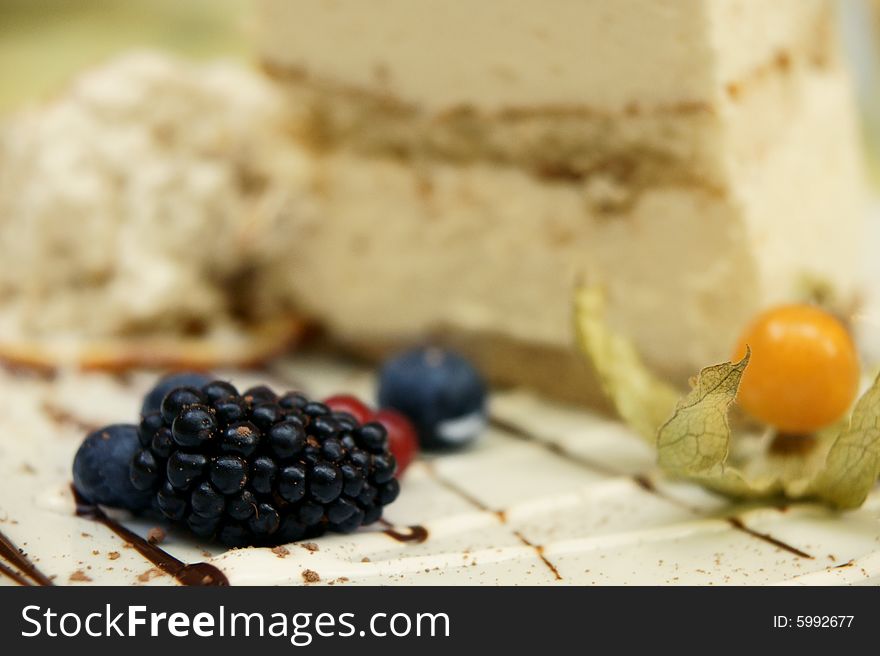 Piece of cream cake decorated fresh berries on white plate, focus on berries. Piece of cream cake decorated fresh berries on white plate, focus on berries