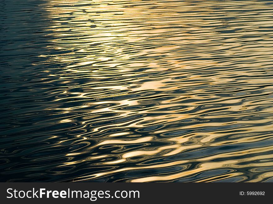 Warm golden tones of a sun reflected on the ripples of a sea surface. Warm golden tones of a sun reflected on the ripples of a sea surface