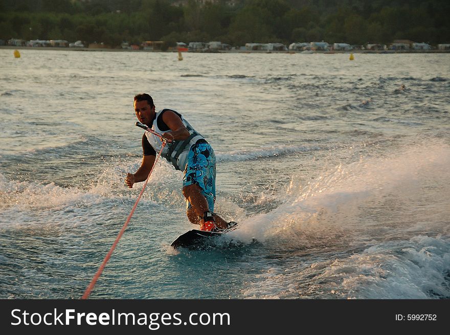 Young man wakeboarding at sunset