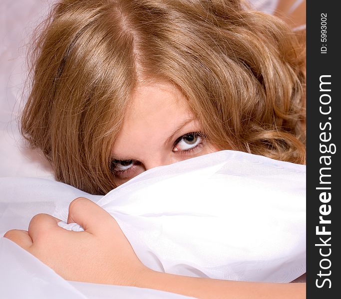 Young blond woman covering her face with pillow