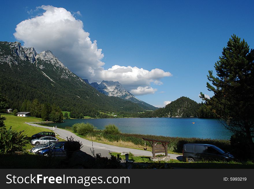 Landscape of Hintersteinersee . lake in Tirol , Austria . Green forest an the rocks on another side of the lake .Mountain ridge Wilder Kaiser above. Not so far from Kufstein city .