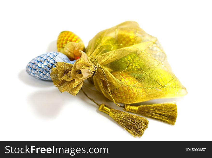 Golden bag full of chocolate pines in a foil on white background