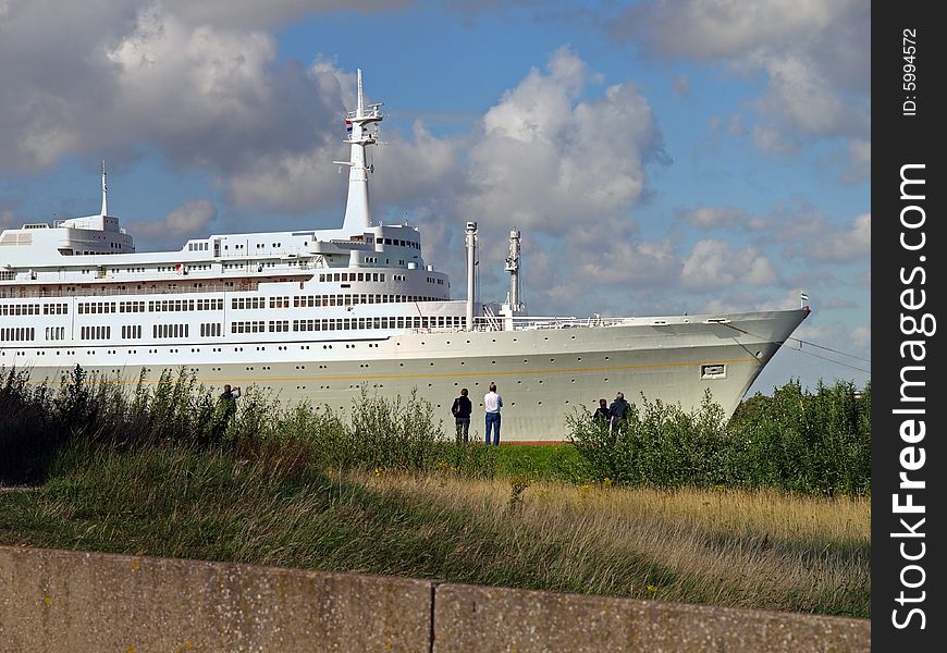 People along the river watching a beautiful passenger ship passing by. People along the river watching a beautiful passenger ship passing by