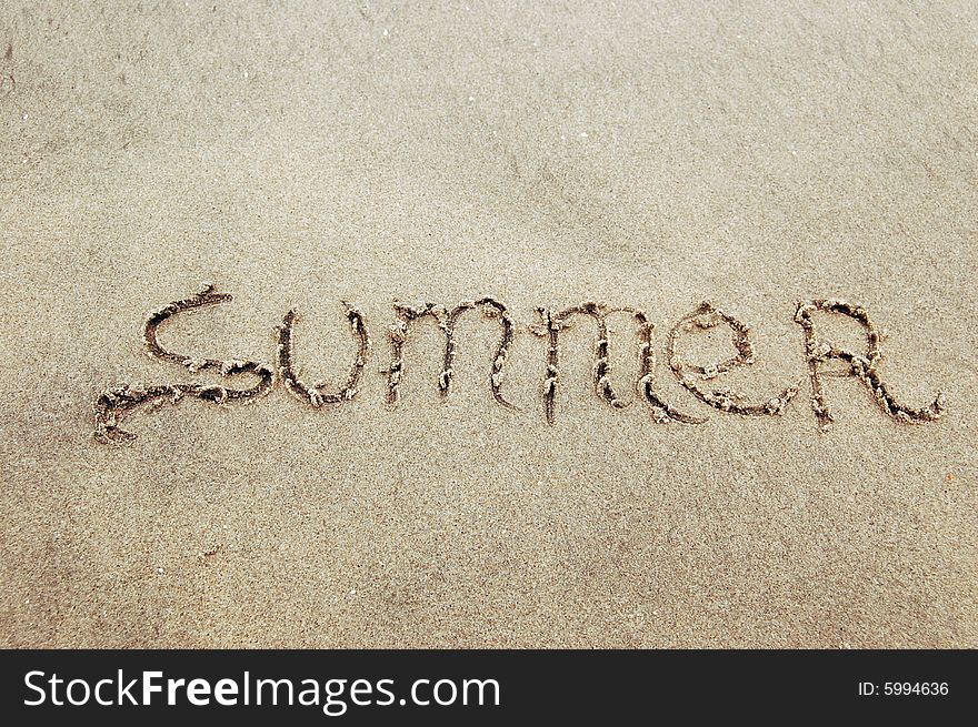 The word summer written on the sand at a tropical beach