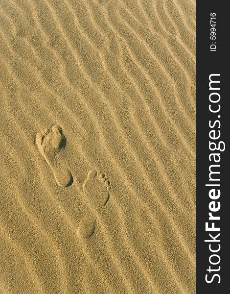 Two footprints on the wavy sand