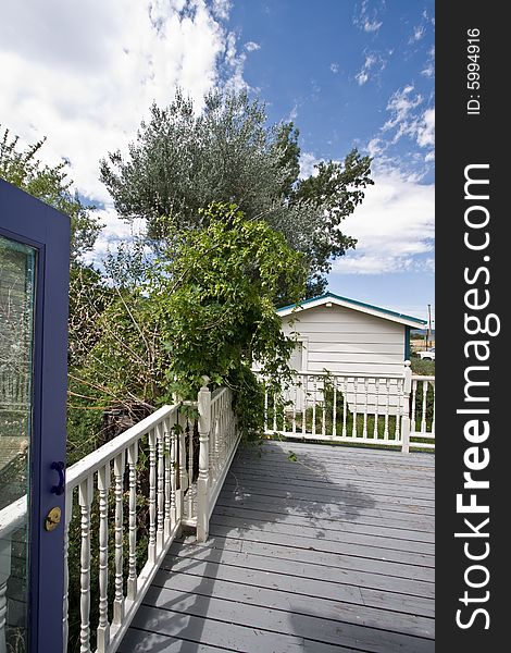 View of deck with wood railing and green shrubs. View of deck with wood railing and green shrubs