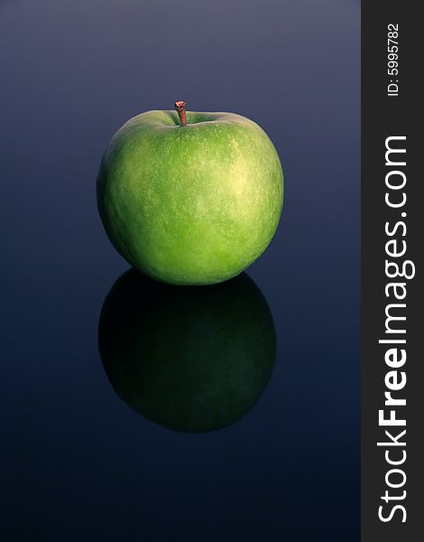 Green isolated apple on blue reflective background,. Green isolated apple on blue reflective background,