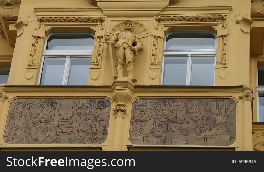The windows of a historic building located by the river Vltava in Prague, decorated with a sculpture of a knight and bas reliefs. The windows of a historic building located by the river Vltava in Prague, decorated with a sculpture of a knight and bas reliefs.