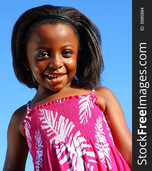 Young girl smiling with blue sky background.