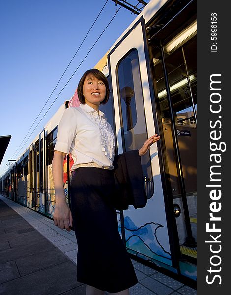Woman boarding train looks over shoulder and smiles past camera. Vertically framed photo. Woman boarding train looks over shoulder and smiles past camera. Vertically framed photo.