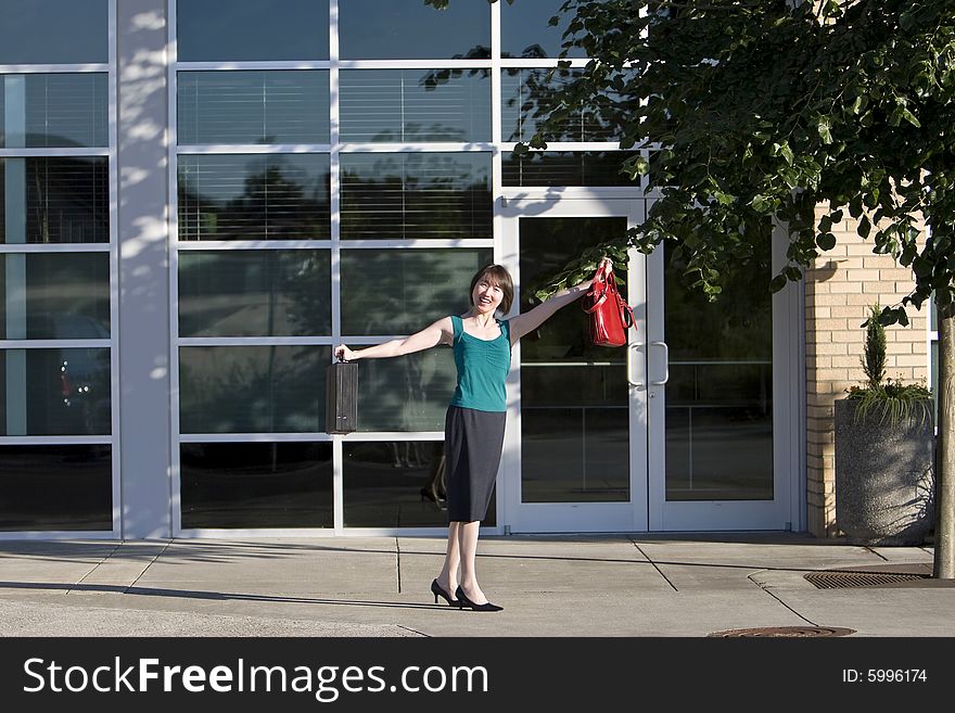 Woman smiles at camera while holding briefcase and red handbag out to her side. Horizontally framed photo. Woman smiles at camera while holding briefcase and red handbag out to her side. Horizontally framed photo.