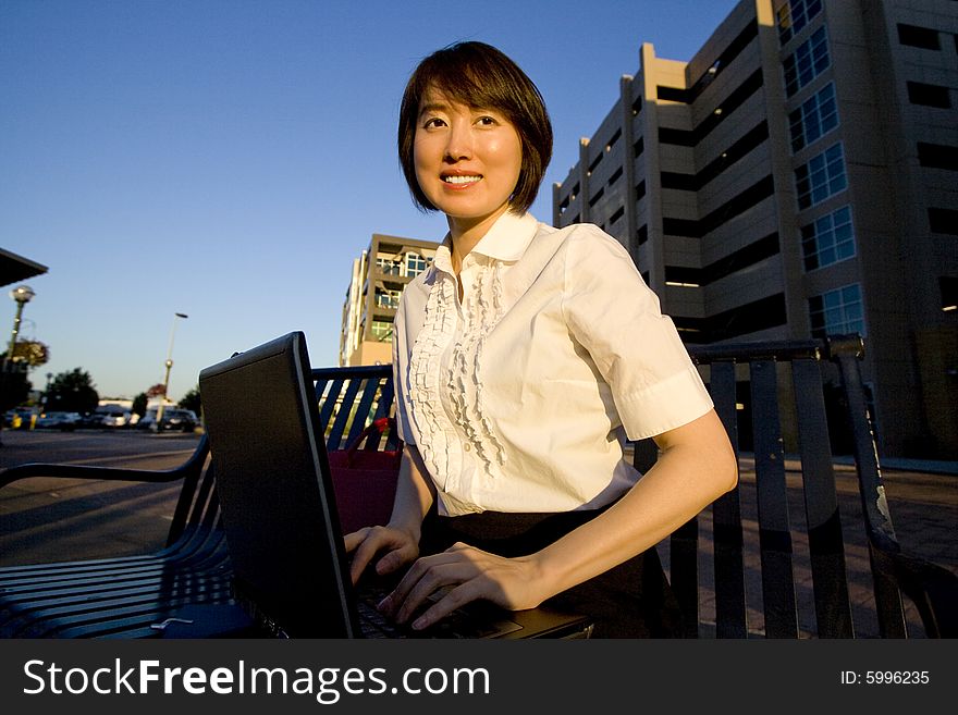 Smiling woman works on laptop while smiling at camera. Horizontally framed photo. Smiling woman works on laptop while smiling at camera. Horizontally framed photo.