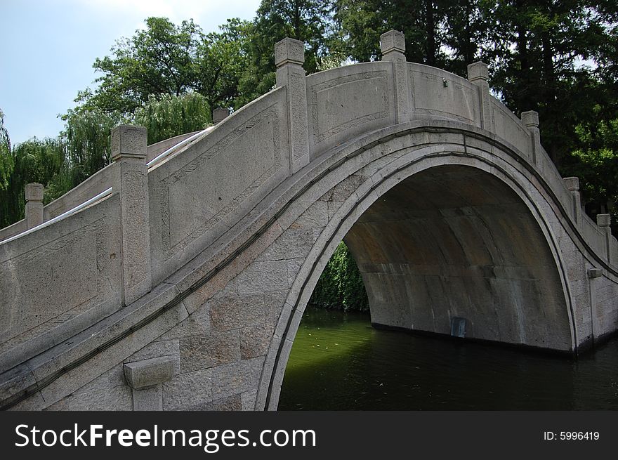 Arch bridge made of rock over a lake