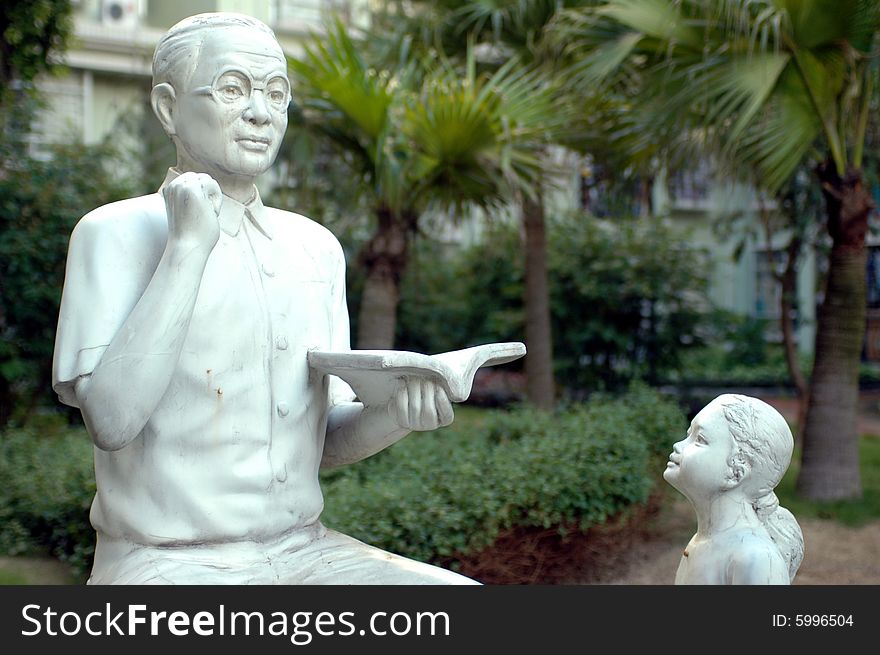 Sculpture made of stone - showing Chinese teacher, holding book and giving lessons to young girl. Sculpture made of stone - showing Chinese teacher, holding book and giving lessons to young girl.