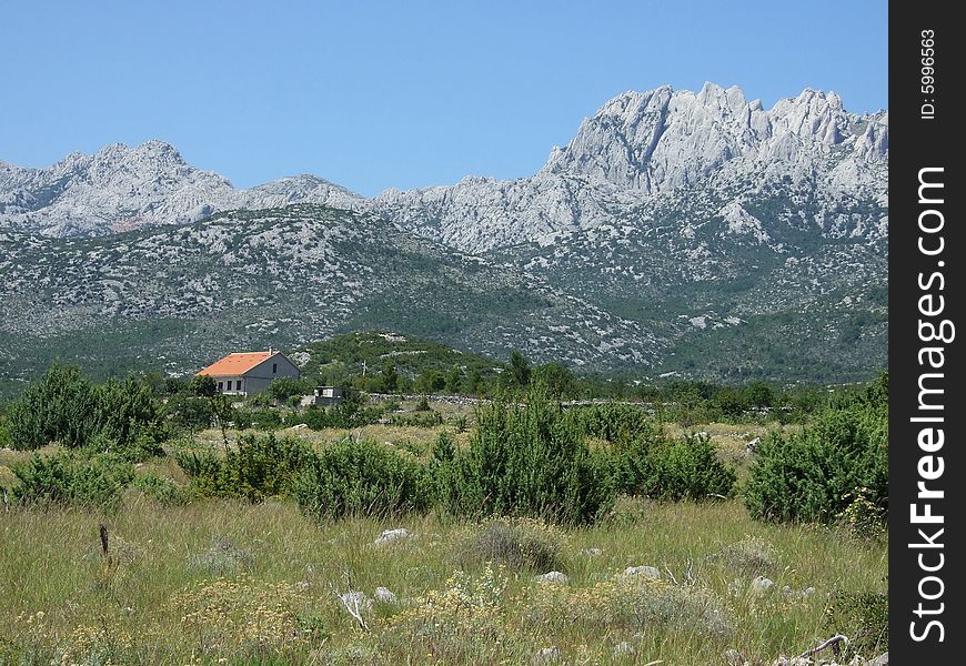 Small red roofed house in the valley by the mountains, Croatia. Small red roofed house in the valley by the mountains, Croatia