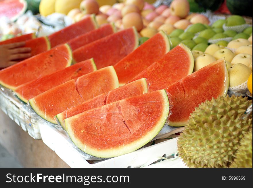 Fresh watermelon, already cut into quarters, ready for sale on market stall.