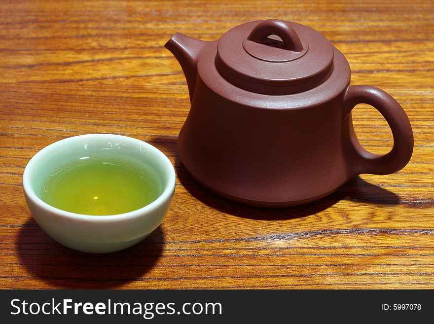 An teapot and teacup on wood background.