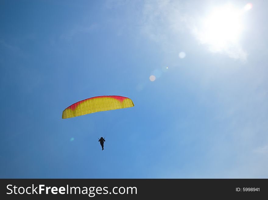 Silhouette of a parachutist in blue sky