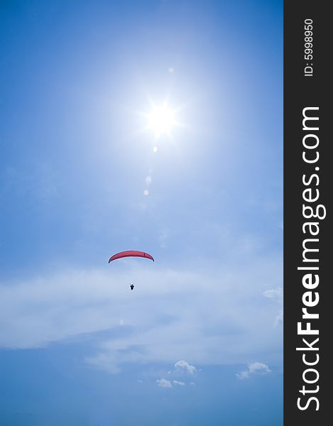 Silhouette of a parachutist with red parachute in blue sky