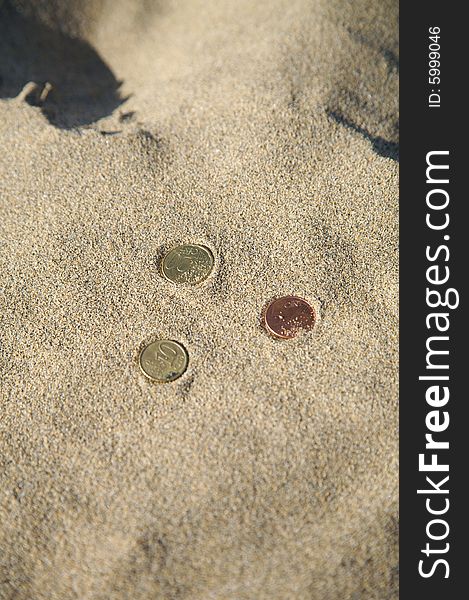 Three euro coins at the sand of a beach. Three euro coins at the sand of a beach