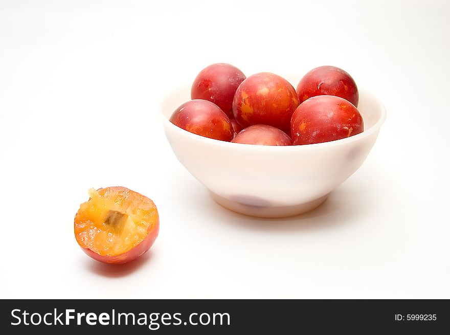 Plums at bowl and  one plum on white background