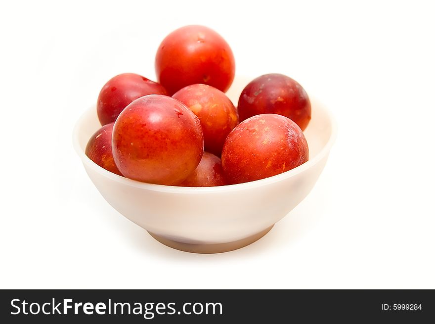 Plums at bowl on white background