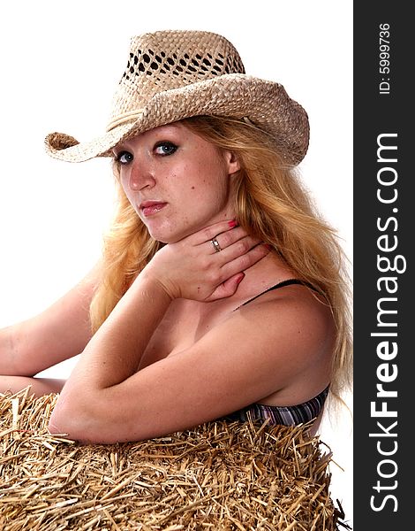 Beautiful and woman wearing a cowboy hat and sitting on a bale of hay. Beautiful and woman wearing a cowboy hat and sitting on a bale of hay