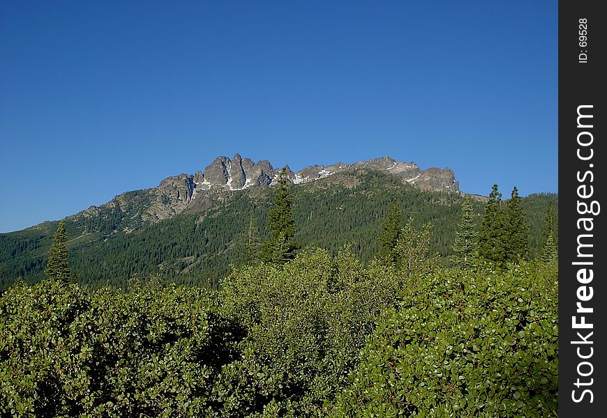 The Sierra Buttes in the Sierra Nevada mountains rises against a blue, blue sky. The Sierra Buttes in the Sierra Nevada mountains rises against a blue, blue sky.