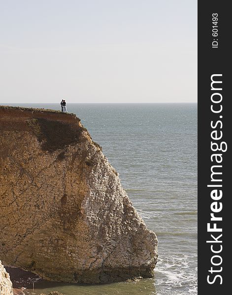 Couple standing on cliff edge overlooking sea