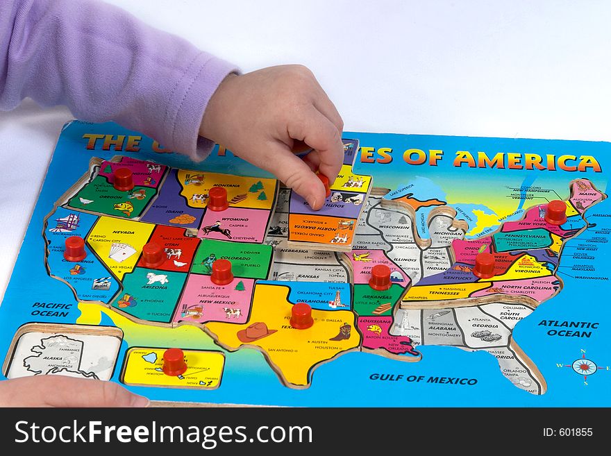 A child putting together a wooden puzzle of the United States. A child putting together a wooden puzzle of the United States