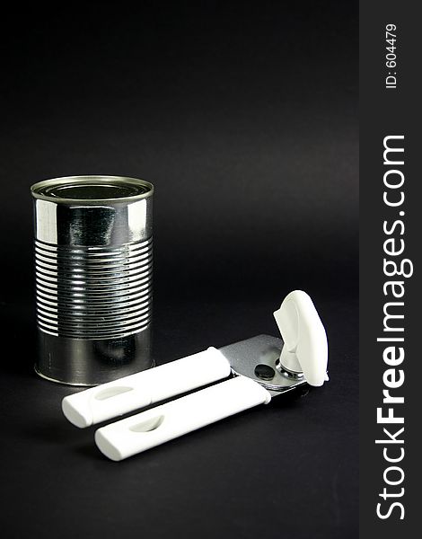 Tin can and tin opener on a black background. Tin can and tin opener on a black background