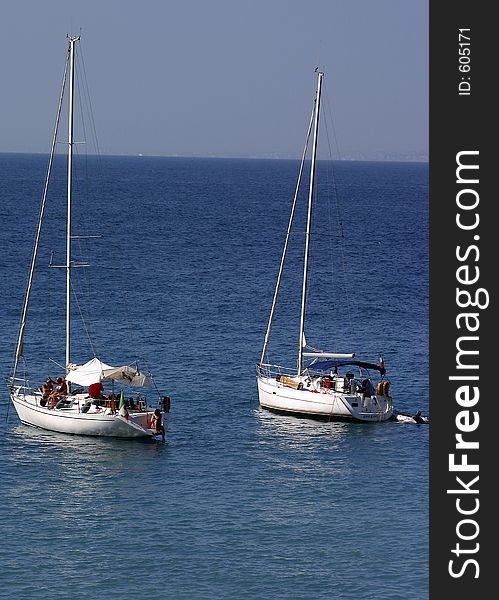 A pair of sailboats anchored in a peaceful bay off the coast of Italy. A pair of sailboats anchored in a peaceful bay off the coast of Italy.