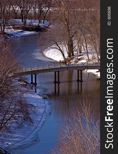 Two people take in the winter scene off small bridge over river. Two people take in the winter scene off small bridge over river