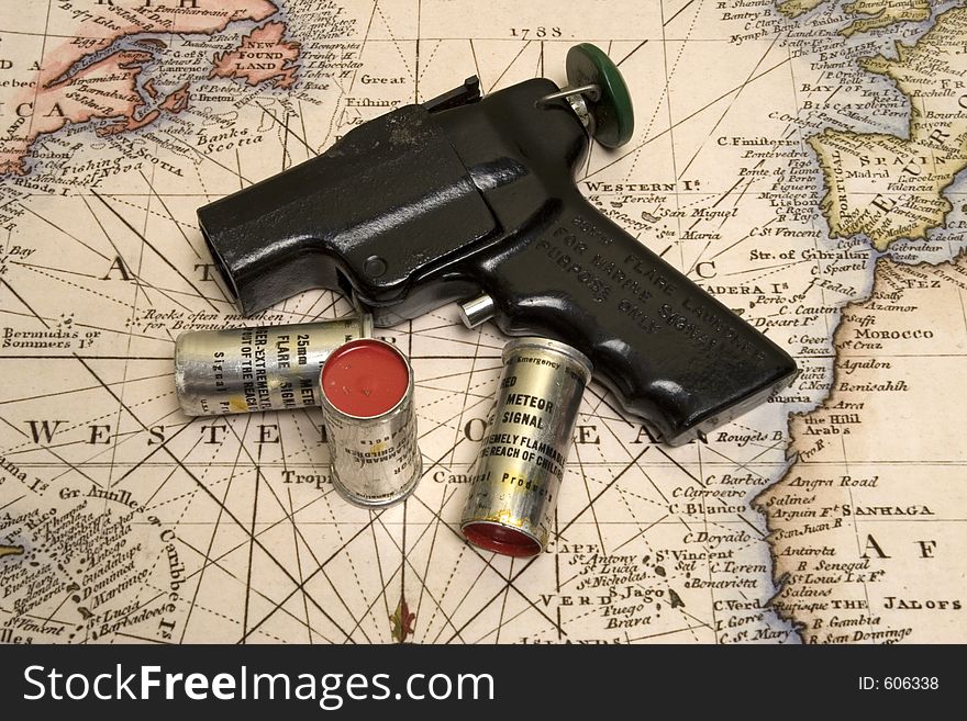 Signal flare gun and 3 rounds on top of old marine map. Signal flare gun and 3 rounds on top of old marine map