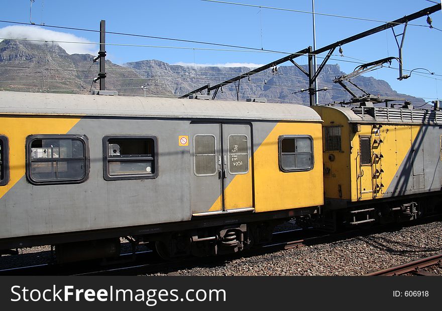 Yellow and grey train infront of table mountain