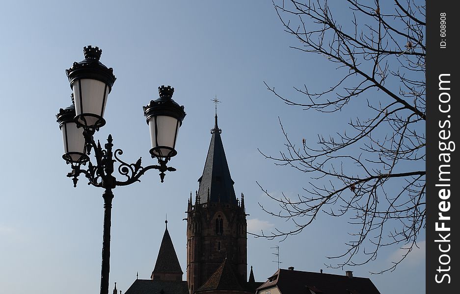 Three streetlamps on one lamppost on the way to Peter and Paul cathedral at the old town of Wissembourg in the Alsace area of France near the German border. Three streetlamps on one lamppost on the way to Peter and Paul cathedral at the old town of Wissembourg in the Alsace area of France near the German border