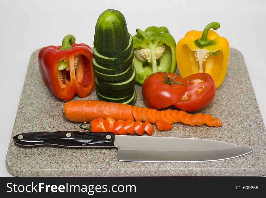 Cut vegetables on a cutting board with a knife.