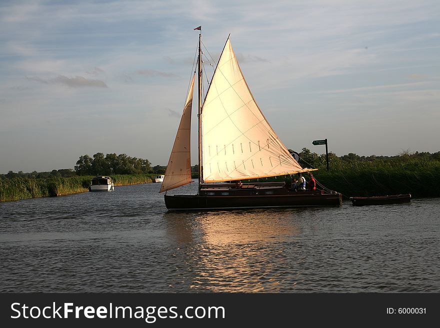 The setting sun lights up the sails of a boat heading home. The setting sun lights up the sails of a boat heading home