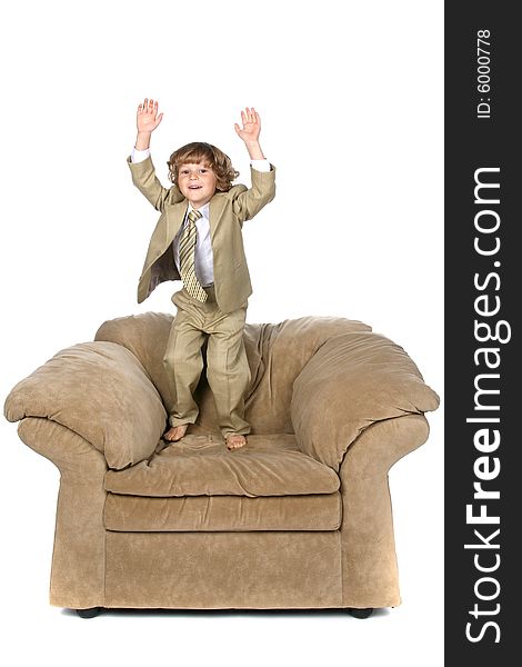 Boy in tan suit jumping on chair. Boy in tan suit jumping on chair