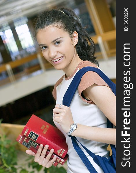 Young beautiful student in college holding books