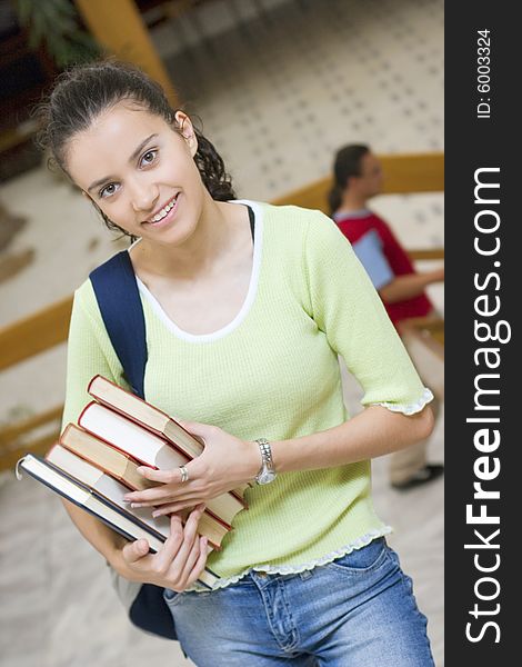 Young beautiful student in college holding books